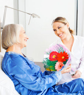 a beautiful woman giving bouquet of flowers to an elderly woman